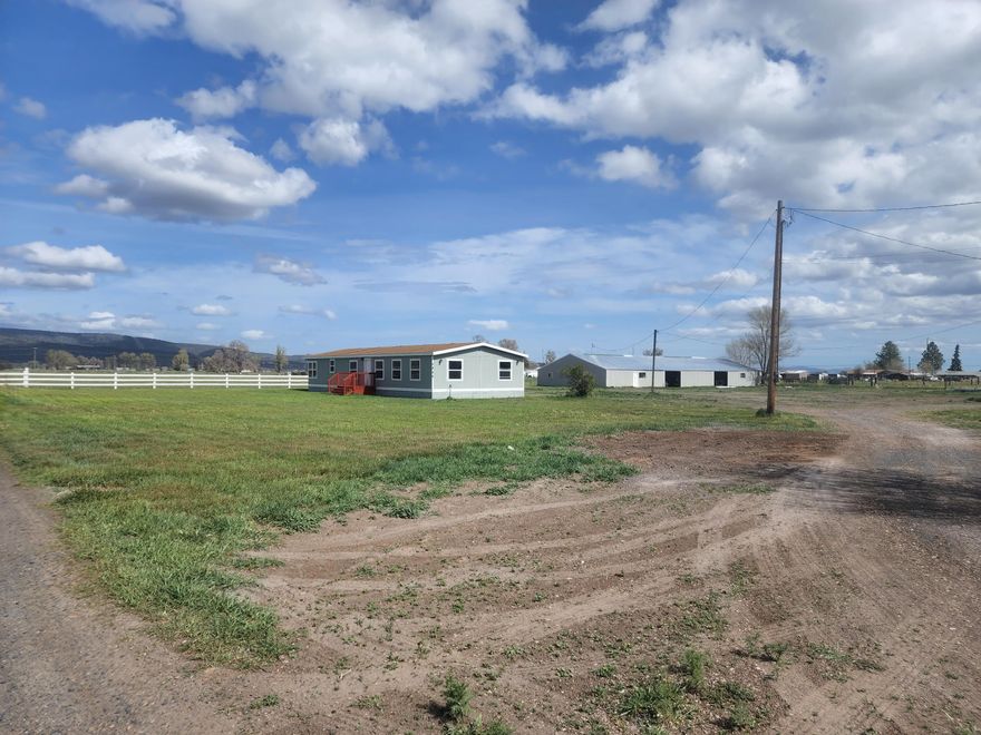 Hard to find irrigated acres on the edge of the quaint little town of Malin.  3-bedroom, 2-bathroom, open living, updated Manufactured home. Property Sits on the edge of town with its own septic, and public water. Flood irrigation keeps the fenced pasture growing.  The barn is oversized and accommodates several possibilities including a tack room, workshop, storage. Many outbuildings, additional workshop, and small shop included. Small 2-bedroom, 1 bathroom 800 sq. ft. home sits on the west side and with some TCL could possibly be additional income, or a guest house.  Don't miss out on a wonderful home with acreage.