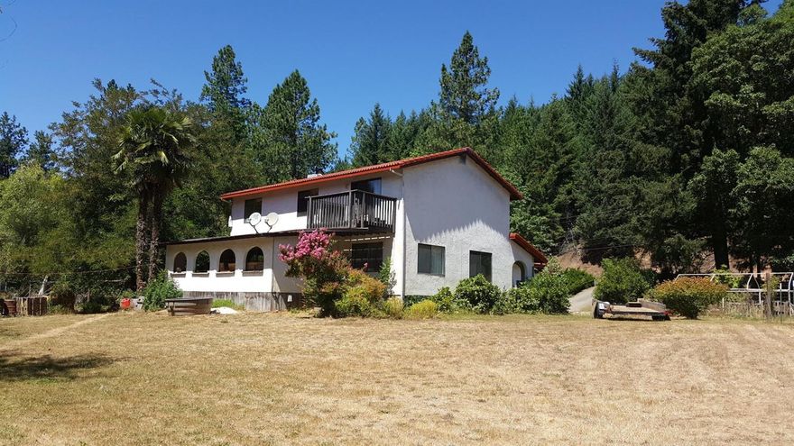 Spanish style 4 bedroom farm house with Mediterranean climate, Palm trees and a beautiful 2.51 acres bordered by Cow Creek with irrigation rights. Fragrant Acacia & Azaleas, wonderful covered Spanish tiled front & back porches; established orchard, cross-fenced garden/animal areas and out buildings. Country kitchen has a newer free-standing gas cooktop/range combo, plus wall oven, fridge w/ bottom freezer, and pantry w/ access to dining room or family room. New energy efficient pellet stove in addition to forced heating/air. 5 foot wide stair case - all bedrooms upstairs. Attached 2 car garage with plenty of storage, work space, deep freezer; as well as a bonus old barn wood'' garage. 8x8 garden shed, 8 x 16 outbldg w/ 2 x8 studs (easy to relocate) Great water production, fertile soils and sunshine, once a garlic farm. This property is quite the mini-ranch and suitable for a horse or cow. Newer Irrigation pump. Needs a little love but don't we all.