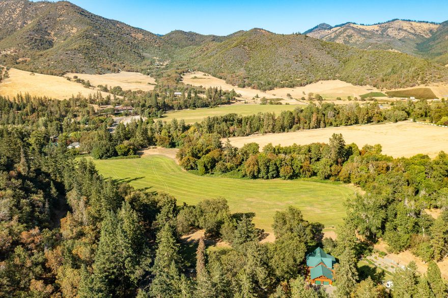 This pristine property boasts natural beauty, outdoor lifestyle, full season water rights, & a stunning log home. As you enter the property through the gate, you are greeted by sprawling lawns & mature trees. The log home welcomes you with an open concept floor plan, soaring ceilings, main level master suite, beautiful views & a gorgeous chef's kitchen. The kitchen was recently updated with all new custom cabinetry, granite countertops, high-quality stainless appliances & more. Outside is a large fenced yard, garden, orchard, chicken coop & deck w/great views. With strong water & class two loam soils, the pasture is ideal for many different crops (Irrigation source: Applegate River & Thompson Creek). The fully finished & conditioned shop is 40x40 & includes a raised center aisle, a winemaking room, wood shop, storage room, & bonus room. Horse barn w/3-stalls, garden shed, woodshed & small vineyard round out the property's features.  1/2 mile from Applegate & 17 miles to Jacksonville.