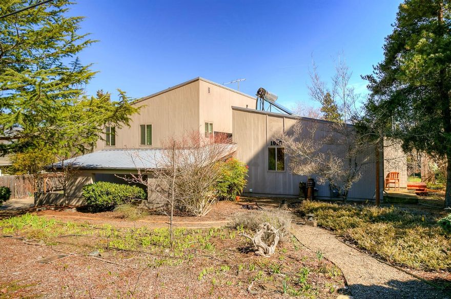 What an incredible property! A cool contemporary style home beautifully connected to the outdoors in a lovely Ashland neighborhood. The living room (with certified wood stove), dining & kitchen w/ vaulted ceilings overlook a large deck, yard & mountain views through generous windows & doors. The spacious master suite has its own deck and open office space. A private guest suite is located on the main level. A bonus room allows several options. The clean, accessible full basement provides storage. The house is in excellent condition w/ more recent upgrades including energy efficient windows & doors & PV solar system. There is a two-car garage, carport and driveway area. This home has easy access being on a virtually flat lot, on a low incline street. The fabulous lot is over 1/3 acre & has been organically gardened for many years with TID watering most of the plantings. Bellview Elementary is a few minutes away; shopping centers, I-5 access & trails are nearby. Just lovely.