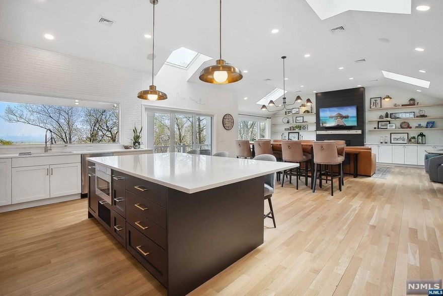 Welcome to your new home, where each day is painted with the vibrant hues of the city skyline. Nestled in Upper Montclair, this nearly 3000 sqft raised ranch is perched atop a secluded wooded lot. A spacious foyer welcomes you, with a sitting & family room to the left, access to the garage, laundry & plenty of storage. As you make your way upstairs you are greeted by panoramic city views, high ceilings, abundance of natural light & radiant heat wood flooring. The open floor plan flows from the kitchen into the living & dining areas, which are anchored by a cozy fireplace. All bedrooms are conveniently located on the same floor. The primary bedroom boasts its own ensuite bathroom, complete with dual closets, and a door leading to the front balcony. Whether you enjoy the heated front balcony, the privacy of the back patio, or the benefits of the open floor plan, this home provides multiple spaces for entertaining & the views that provide the perfect backdrop for every occasion.