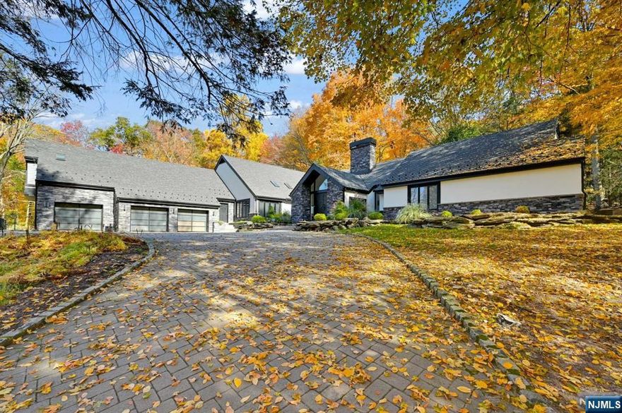 Welcome to this stunning, updated contemporary home nestled in one of Saddle River's most sought-after neighborhoods, just 30 min. to NYC. This residence effortlessly blends modern luxury with rustic charm, featuring soaring ceilings and antique barnwood flooring. The expansive layout offers a thoughtfully designed living space, including an impressive primary suite with a spa-like primary bath, complete with a glass-enclosed shower, a separate soaking tub, and plenty of space to relax and rejuvenate. The large finished basement is a recreational haven, featuring a bar area, workout space, and ample room for entertaining or play. Perfect for car enthusiasts, the 5-car garage provides an abundance of storage and space for your prized vehicles. Set on a breathtaking 2-acre property, the outdoor amenities are equally impressive. Relax on the paver patio by the gorgeous pool with waterfall and koi pond. Also enjoy the covered patio, sundeck, and additional patios off dining/living.