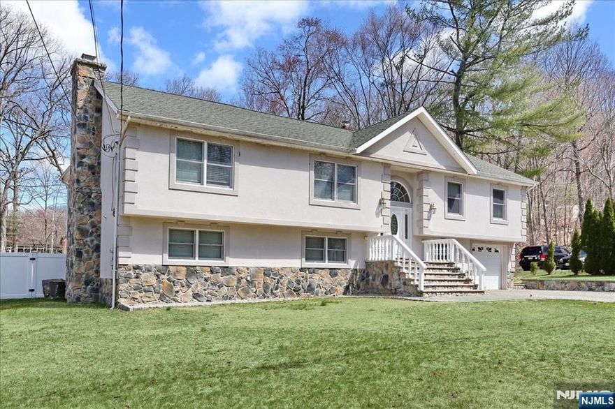 Welcome to this spacious and thoughtfully expanded bi-level, set on a generous, flat, fully fenced yard ideal for everyday living and entertaining. A distinctive stucco exterior and paver driveway add curb appeal, while recent updates including refinished hardwood floors, fresh interior paint, and a fully renovated bathroom make this home truly move-in ready. The flexible layout offers four bedrooms, two and a half baths, and two full kitchens, providing exceptional versatility for hosting, extended stays, or creating dedicated work and living spaces. The upper level features a bright open living and dining area, an updated kitchen, and access to a large deck overlooking the private backyard. The expanded primary suite includes an en-suite bath and space for a sitting area or home office. The lower level offers a cozy family room with fireplace, a second full kitchen with dining area, additional flexible space for an office or den, a large laundry area, and direct access to the attached one-car garage. Optional lake membership allows for seasonal swimming, kayaking, and community events just minutes away. This well-maintained home delivers space, flexibility, and lifestyle in a setting you'll love.