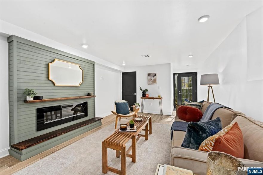 **PRIVATE BACKYARD + PARKING** Your next chapter begins at 201 Zabriskie #1, a beautifully redesigned two-story home in the heart of Jersey City Heights. Spanning nearly 1,800 square feet, this spacious 3-bedroom, 2.5-bath residence perfectly blends smart function, design, character, and comfort. This is true modern city living, complete with a fully finished private backyard and valuable private, off-street parking. Tucked away just moments from Leonard Gordon Park, Tonnelle Avenue, and the Holland Tunnel, this peaceful retreat offers quick access to the energy and amenities of the Heights and NYC. Step inside to a bright, open-concept main level. The living area is instantly inviting, centered around a cozy fireplace featuring a custom wood mantle and shiplap detail. Wood tile floors and custom lighting flow seamlessly into the full-size dining area and the gourmet kitchen, designed equally for everyday living and stylish entertainment. The kitchen is a sleek contemporary dream with Calcutta Bellow white quartz waterfall countertops and matching backsplash, custom cabinetry, and black stainless steel appliances and fixtures. It also boasts a large eat-in island, perfect for casual meals or larger gatherings. While the main level hosts two sizable bedrooms, each with a walk-in closet, the upper level is dedicated entirely to the private primary ensuite, offering a secluded sanctuary.