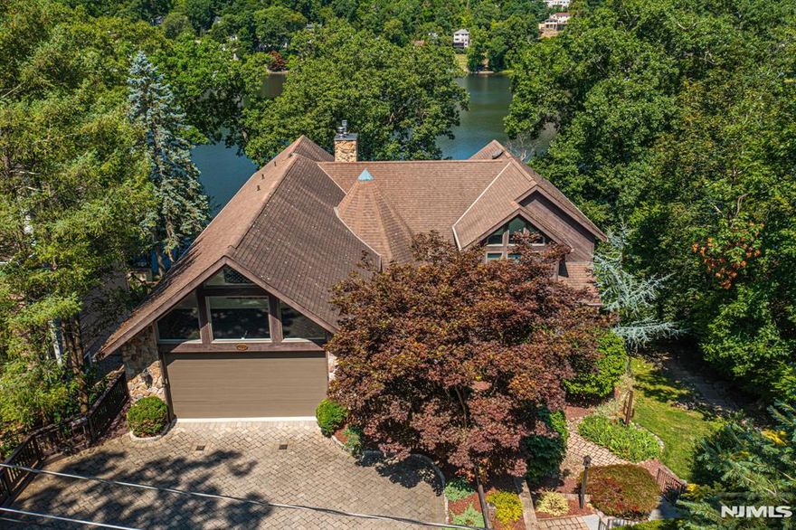 Stunning Cedar Lake Waterfront Retreat! This exceptional custom lakefront home offers over 4,000 sq ft of beautifully designed living space with breathtaking views of the Lake from nearly every angle. The dramatic interior features cathedral ceilings, walls of windows, & a striking floor-to-ceiling stone gas fireplace that anchors the main living area in warmth & elegance. A true highlight is the 1-floor primary suite, complete with a balcony overlooking the lake, creating a peaceful retreat with incredible views. The spacious layout is ideal for both everyday living & entertaining, seamlessly blending indoor comfort with the natural beauty of the waterfront setting. Upstairs, an additional 2 bdrms & den. The home includes 4.5 baths, an oversized 2 car garage, paver driveway & a full, walk-out bsmt, offering endless potential for future living space or storage. Outdoor living shines with a multilevel trex/cedar deck and private dock, perfect for enjoying sunsets, lake activities, & the serene surroundings. Motorized awnings shade the Western front. A rare opportunity to own a truly custom waterfront home with remarkable space, architectural character, & unforgettable lake views in desirable Denville. Rectangle shaped lot in a private section of the lake community. Public sewer hookup available for future use. Generator hookup. Close proximity to DWTN Denville & Boonton Main with all its shopping, dining & events with easy access to major highways & NYC direct transit.