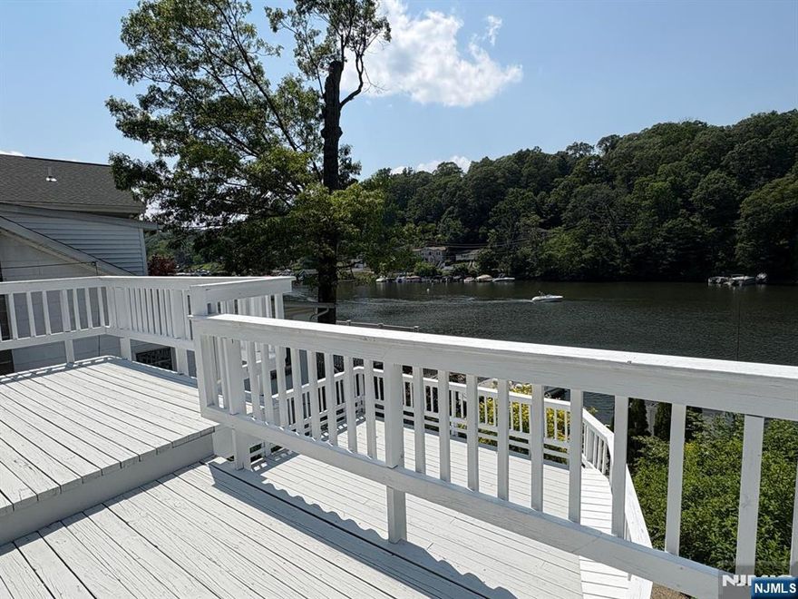 STUNNING LAKEFRONT HOME located on one of the calm/peaceful sections of the largest lake in NJ. This beautifully crafted home features 3 bedrooms and 2 full bathrooms, perfect for gatherings or a peaceful retreat. As you enter, you're welcomed by a warm and inviting living room with a wood-burning fireplace and glass sliding doors leading to the large balcony overlooking the lake. The 3 bedrooms and 1 full bath are conveniently located on the same floor. The kitchen, next to the second full bath, down the steps, has granite countertops, an eating area with views of the lake, and sliding doors leading to the very large deck. Venture down the exterior steps to discover a cozy patio area with a BOAT HOUSE, perfect for water enthusiasts to store watercraft and gear with the potential to build a deck on the roof for even better views! The house is heated by electric baseboards and air-conditioned by ductless mini splits. This home has a New well tank, pump and new sophisticated filtration system and PUBLIC/MINUCIPAL SEWER. 2 car driveway, laundry hookups, incredible views and minutes to major routes. Do not miss your chance to own this remarkable LAKEFRONT home - your dream getaway awaits! The property is vacant and ready for move in!