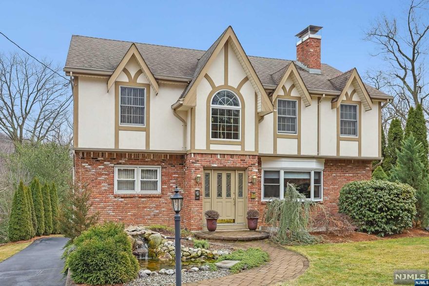 Unbelievable opportunity for this stunning English Tudor, offering 4 bedrms and 4 full baths. This beautifully maintained home greets you with a Koi Pond! Enter into the double height Foyer, Living rm w/free standing wood-burning Fire Place. 1st floor boasts a 21 x 13 updated Eat-in-kitchen w/slider to large updated deck, which wraps around to other end of kitchen w/side entrance. Stainless appliances, granite countertops, beautiful back splash, also full bath, Dining rm, 1st fl bedrm & wood flrs throughout to finish the main level. 2nd fl offering large Master Bedroom Suite w/walk-in closet, master bathrm w/jetted tub, double sink & shower. 2 additional bedrms & full bath. Make your way to a finished basement w/Family Rm w/wood-burning Fire Pl, walk-out basemt to yard. Utility /Laundry/ Bathroom w/shower & separate rm w/private toilet. Large driveway leads to 2 car garage, additional parking. Rear yard tiered with natural stone steps to paver patio close prox to 23 & 287