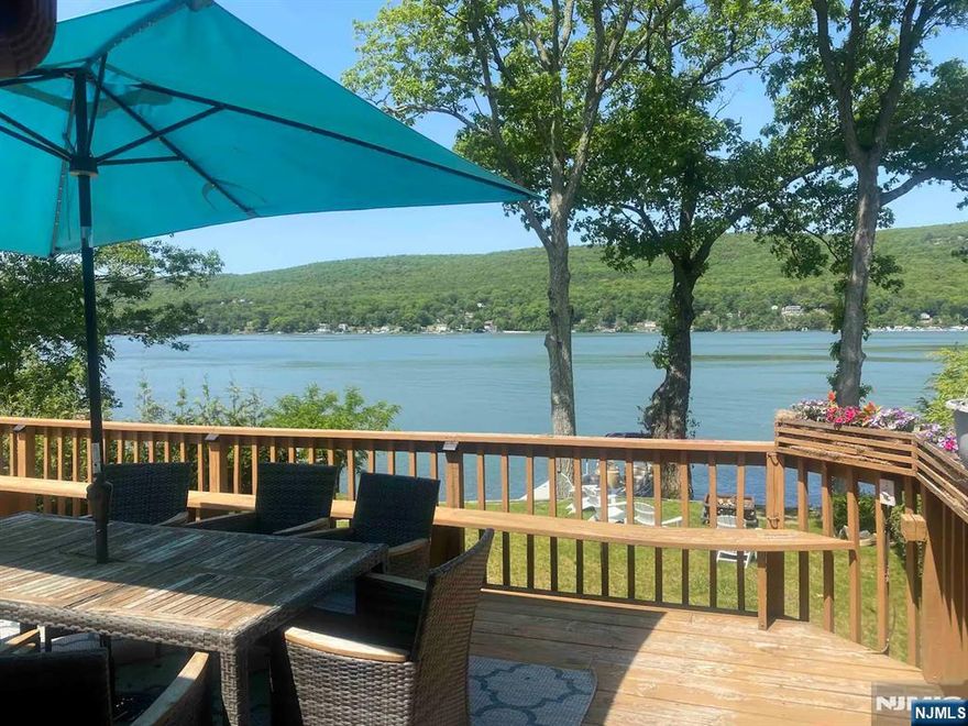 Waterfront residence on Greenwood Lake featuring 4 bedrooms and 2.5 baths with 50 feet of lake frontage and a private dock. This light-filled home offers vaulted ceilings, skylights, and an open kitchen and dining area with a wall of windows showcasing beautiful lake views and sliders leading to a spacious deck for relaxing or entertaining. The main level includes two bedrooms and a full bath with laundry, while the second floor offers the primary bedroom, an additional bedroom/bonus room, and a powder room. The walkout lower level features a rec room with wet bar, full bath with walk-in shower, and access to the patio and backyard, plus an 8-person hot tub to enjoy year-round. Conveniently located near the NY border and close to skiing, wineries, orchards, and Warwick, NY. 3-bedroom town verified septic.