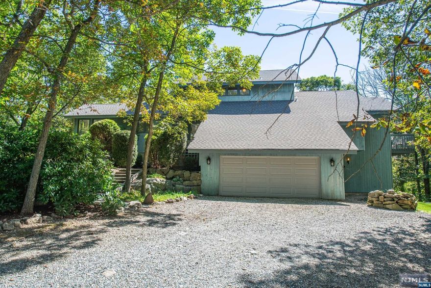 This custom home, set in a serene wooded landscape, is designed for multigenerational living. The main living area features an open-concept layout with high ceilings, a large eat-in kitchen with expansive windows, and stunning wooded views. The living and dining room boast a double-sided wood-burning fireplace, access to a wraparound deck, and beautiful laminate flooring. The third level offers a private primary suite with French doors, two walk-in closets, and a full bathroom. A separate in-law suite or guest quarters in the finished basement includes its own entrance, kitchen, living area, and bedroom, ensuring privacy and independence. Multiple outdoor spaces provide a perfect setting for enjoying nature, from morning coffee on the deck to evening gatherings around a fire pit. Spacious bedrooms, elegant finishes, and modern amenities make this home both functional and beautiful, complemented by its tranquil, natural surroundings.