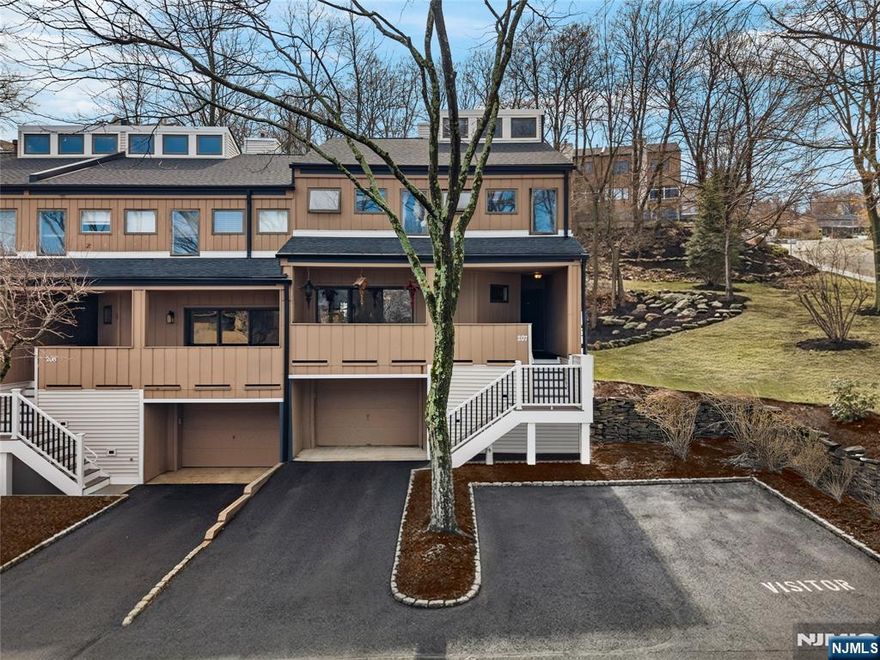 This distinctive corner unit offers approximately 3 bedrooms and 2.5 baths, along with one of the largest private outdoor spaces in the community. The fenced patio features a gazebo, seating areas, and mature plantings ideal for entertaining or unwinding in privacy. Enjoy a front balcony and decorative Juliet balcony, with NYC skyline views on clear days.Inside, a gallery-style entry leads to a formal living room and open kitchen/dining area with a convenient main-level half bath. Upstairs includes a primary suite with en-suite bath, a flexible family room or additional bedroom, and an open loft for storage or creative use. The lower level adds two rooms suited for office, flex, or storage needs.Located in a safe, quiet, and highly desirable neighborhood, close to parks, dining, Willowbrook Mall, and major routes including I-80, Routes 46 & 3, this home delivers privacy, flexibility, and standout outdoor space rarely found in the area.