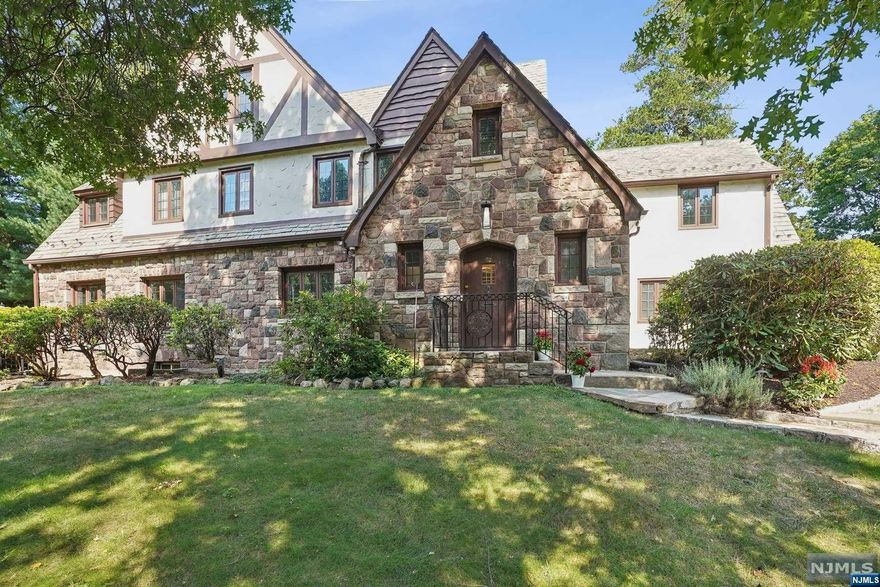 This stunning Tudor home offers a blend of elegance and modern comfort, ideal for both relaxing and entertaining. The heart of the home is its spectacular kitchen, featuring marble countertops and an island with seating for five, perfect for casual meals or gatherings. The first floor includes a formal living room with a gas fireplace, a spacious dining room that opens directly into the kitchen, a sun-filled solarium with exposed brick, and a private office. The primary suite is a retreat in itself, boasting a coffee bar, a large dressing room, and a luxurious bathroom with radiant heat floors, a large soaker tub, and a vaulted ceiling with exposed beams. The fifth bedroom features a vaulted ceiling with beams and a full bath, making it an excellent guest suite. The third floor offers two additional bedrooms, an updated full bath, an exercise room, and walk-in storage, providing plenty of space for family and guests.