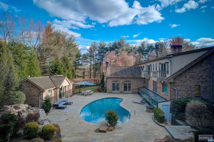 Welcome to this home in the High Ridge section of Saddle River, set on a generous two-acre plot offering privacy and space. This inviting estate is well-maintained, featuring marble floors, a large living area, a cozy library, and a classic dining room for gatherings. Spacious traditional kitchen offers plenty of storage and a sunny breakfast nook. Retreat to the comfortable primary bedroom on the first floor, which includes a fireplace, a private bath, and two walk-in closets for ample storage. The lower level has been refreshed to include an entertainment area with a fireplace, a convenient kitchenette, a bathroom with spa touches, a gym area, and a spacious in-law suite with its own exit. Upstairs you have four large bedrooms and two full baths. The backyard is your own private retreat with a fenced pool area, waterfalls, and a pool house with essential amenities. Located just minutes from NYC, this home offers a peaceful lifestyle while remaining close to city conveniences.