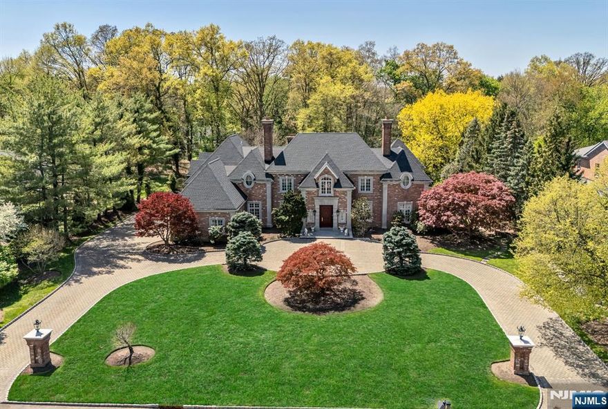 Experience a grand, inviting retreat, crafted by a premier builder and designer, Jim Nigro. This all brick estate rests on a solid, poured-concrete foundation w/ steel support beams, marrying timeless elegance w/ enduring strength. Gracious layout provides options for the discerning buyer including 5 bedrooms, all ensuite, including a stunning primary suite w/ a private balcony overlooking a pristine backyard. The 2 story grand entry soars to 20 feet, featuring a walnut, bridal staircase and custom Anchorbolt spindles that greet you w/ timeless warmth and sophistication. Interior woodwork and trim are meticulously handcrafted using only real wood for a rich, enduring beauty throughout. Chef grade comfort meets everyday joy in the Allmilmo kitchen which opens to a spacious breakfast dining area and a private study or playroom, perfect for family gatherings, homework and quiet moments. Formal living and dining rooms, library, the great room and primary bedroom all feature gas fireplaces adding inviting warmth and architectural charm. Lower level is fully finished and updated with modern porcelain tile, offering flexible space. Full house generator, surveillance system, hardwood flooring, circular drive, 3 car garage, specimen trees and a top rated town and schools enhance the appeal. This masterpiece offers a rare blend of grand craftmanship, contemporary comfort and heartfelt warmth, perfect for growing families, entertaining and anyone seeking a refined sanctuary.