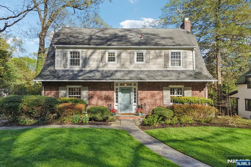 From the moment you arrive, this extraordinary Dutch Colonial impresses with character, craftsmanship, and timeless warmth. Enter the grand foyer and you are greeted by rich hardwood floors, soaring ceilings, and extensive millwork throughout. A wrought iron staircase rises to a sweeping balcony above, a breathtaking first impression. The main level flows beautifully. The spacious living room, anchored by a fireplace and built-ins, connects through pocket French doors to a family room spanning the rear of the home with a windowed wall of views to the backyard greenery. It connects to a sun-drenched eating area off the chef's kitchen, where a center island takes center stage and a back staircase adds easy functionality. A formal dining room and powder room complete the first floor. Upstairs, the primary suite offers a full bath with spa tub, joined by three additional bedrooms, an updated hall bath, and second-floor laundry. The third floor adds two more rooms that function as bedrooms or offices with a full bath. The finished lower level features a rec room, gym, small resistance pool, and mudroom. Outside, the backyard is expansive and lush with mature trees, a sweeping lawn, and a tucked-away fireplace area perfect for cool evenings. Located in one of Ridgewood's most idyllic neighborhoods, just moments from a bustling downtown, great dining, shopping, easy NYC access, and top-ranked NJ schools. This your home sweet home!