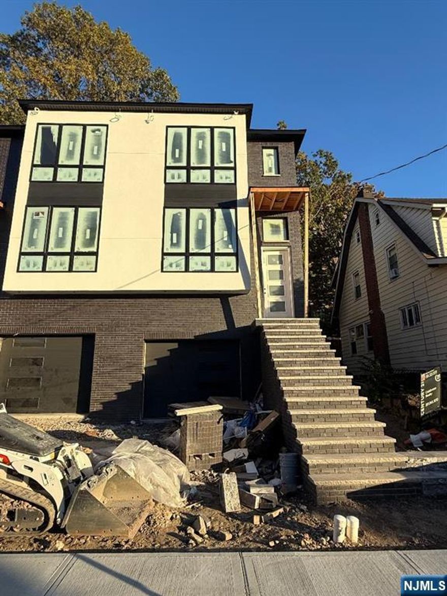 Be the first to live in this beautifully built, brand new half duplex located on a quiet, tree-lined residential street just moments from convenient NYC transportation. This modern home offers a thoughtfully designed layout, beginning with a welcoming living room featuring a cozy fireplace, a formal dining area, and a stylish kitchen with sliding glass doors that open to a private patioâ€”perfect for indoor/outdoor living. A powder room completes the main level. Upstairs, the spacious primary bedroom includes a private en-suite bath, accompanied by two additional bedrooms, a full hall bath, and a conveniently located laundry area. The ground level offers a versatile recreation room with a full bath, ideal for a guest suite, home office, or entertainment space, plus direct access to a one-car attached garage. Enjoy all the benefits of new construction, modern finishes, and a prime location with easy access to city commuting, parks, and local amenities. Move-in ready and built to impress!