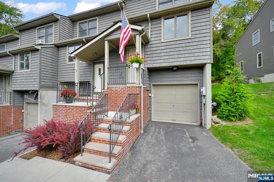 Open-concept living meets designer flair in this stunning end-unit at Mountain Ridge Townhomes! The beautifully updated kitchen features refreshed wood cabinetry, stainless steel appliances, and a custom center island that's perfect for entertaining. A stylish powder room with elevated finishes and a separate dining area overlook the sunken living room, complete with custom built-ins and sliding doors to your private deck. Step outside to enjoy scenic views, multi-tiered gardens, and peaceful privacy backing to state land. Hardwood floors flow throughout the first level and hallways, adding warmth and continuity. Upstairs, the spacious primary suite offers newer carpeting, three custom closets, and a full bath with double vanity and stall shower. The second bedroom includes fresh carpet, a large double closet, and access to a full hall bath with shower/tub combination. Stackable washer/dryer in hall round out the second floor. The finished basement, with wood-look tile, makes the perfect home office, gym, or rec room. An oversized garage off the basement provides space for a car, motorcycle, additional refrigerator, and abundant storage. Recent updates include bedroom carpet + window treatments (2025), garage door opener, belts, and remote (2025), kitchen refrigerator (2025), roof (2024), HVAC (2023), water heater (2021).