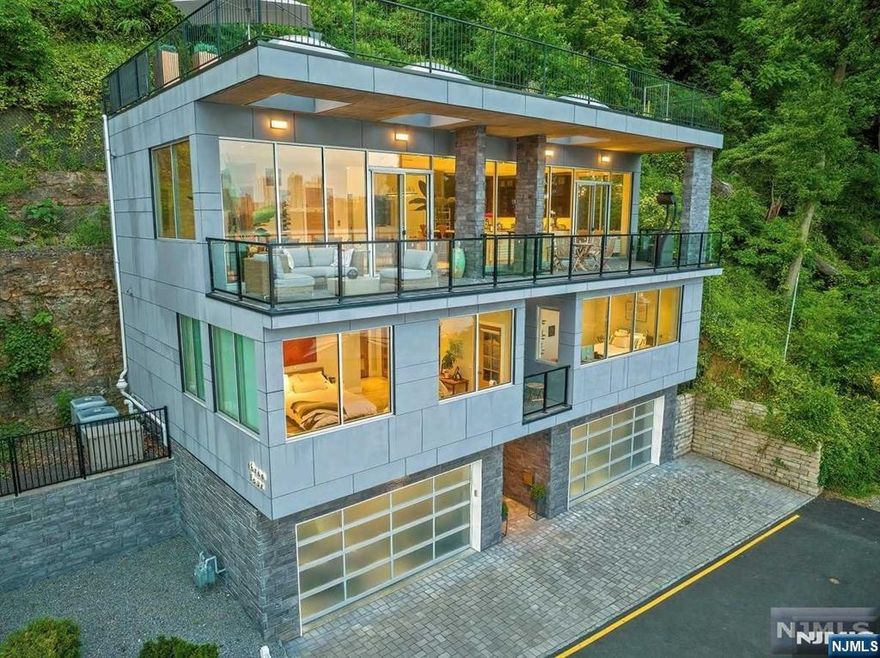 Captivating contemporary living in the Colony. Perfectly private, 34 Shore Road showcases iconic Hudson River and Manhattan skyline views from each room while offering an escape from the city with direct access to a 2,500 acre park featuring hiking, biking and boating. Inside, a striking tempered glass staircase and oversized elevator with an 8-foot interior add both drama and convenience. Entertain effortlessly with seamless open-concept layout, floor-to-ceiling windows and sliding doors to a serene terrace, gourmet kitchen with dual island and a private 1,200 sq. ft. rooftop terrace â€” all set against breathtaking panoramic views of the Manhattan skyline. The primary suite features a coffee terrace, large walk in closet and en-suite bath with dual vanity, steam shower and tub. Additional highlights include 10 zone radiant heat, 4 car garage, a 245k BTU McClane high-efficiency boiler, contemporary stone façade for low-maintenance living, Lutron smart lighting with remote access and a thoughtfully designed floor plan emphasizing light, flow, and function. Colony residents also enjoy community amenities including a full fitness center, clubhouse, and private waterfront park. A rare opportunity to own a one-of-a-kind modern masterpiece just minutes from Manhattan.