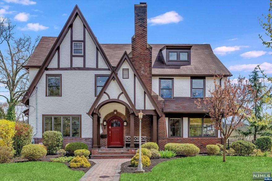 Nestled between Anderson & Edgemont Parks, steps to NYC trains & Upr Montclair Village shops/restaurants, this gracious Tudor awaits! Surrounded by gardens accessed from multiple sets of French doors, you'll love entertaining this summer! The large LR is perfectly balanced by the woodburning fireplace and wall of custom built-ins. The Sunroom leads to the charming, covered porch, and is the perfect Office, TV Room or Playroom. The formal DR, kitchen w/induction cooktop plus separate 6-burner range, dbl oven, SS appl, large pantry & ctr island, will make meals a breeze. Upstairs, is the huge Primary Suite w/walk-in closet & dressing room, dual vanities, separate shower and soaking tub, WC, heated towel bars. Two more large BR's and Hall Bath w/radiant heat, complete this level. The 3d floor has two more BR's, Full Bath and Attic storage. Radiant heat throughout 1st floor and Primary Suite. 2-zone A/C. Plus, lovely brick patio, firepit area, detached 2 car garage w/Tesla charger.