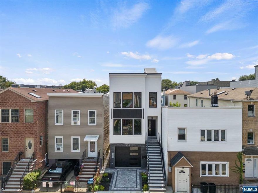 A striking opportunity to own this luxurious 2-Family property, an impressive ground-up brand new construction in Jersey City Heights! Total of 6br & 5ba. Both units feature a spacious living room with an elegant geometric accent wall & electric fireplace, large windows that flood the space with natural light, and hardwood flooring throughout the entire home. Sleek, modern kitchen with calcutta quartz countertops, kitchen island and state-of-the-art stainless steel appliances, including Wine Fridge! Primary bedrooms feature warm wooden accents, an elegant en suite bathroom, generous sized walk-in closet and direct access to your own private balcony for a quick sunbath or airy relaxing escape. Unit 1 has an exclusive access to the backyard and Unit 2 has its own private full size rooftop deck for city skyline views! 2 cars can fit in the garage, tandem-shared parking. Close to Washington Park, shops, restaurants, schools and public transpo to NYC! *virtually staged photos