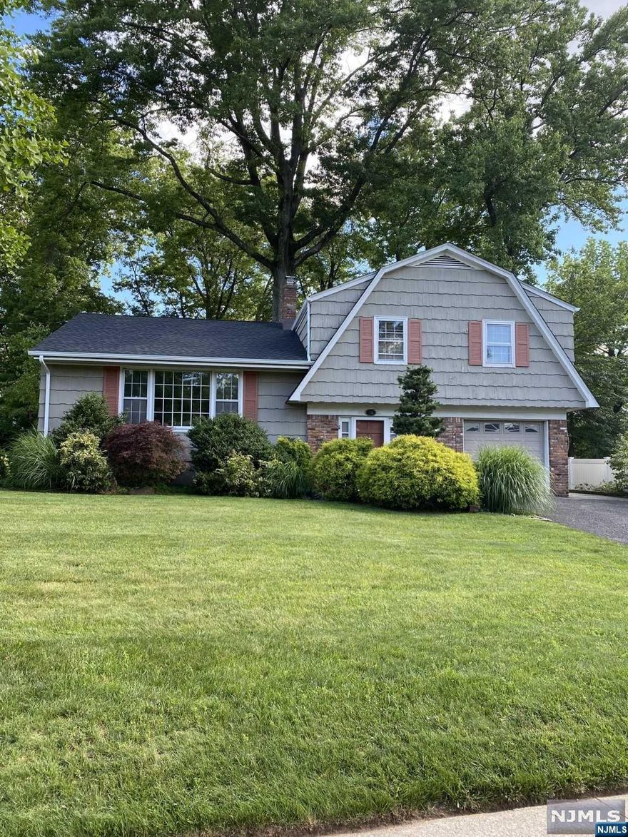 Impressive sugar maple split level on East hill. Magnificent park-like property with mature shrubs and majestic trees that cool this well sited home. Recently painted, custom crown molding, beautiful hardwood floors. Alno custom jasmine lacquer cabinets, Sub-Zero, newer dishwasher and door to tiered deck. A Master BR ensuite, 2 additional generous bedrooms and another full bath/skylight upstairs level. Closets galore, storage attic and pro dry basement. The family room with French doors to backyard paver patio can be a private guest suite with its summer kitchen and full bath. Owner has NJ RE License. Wonderful location walk to NYC bus,School,shopping, restaurants and school. HURRY!