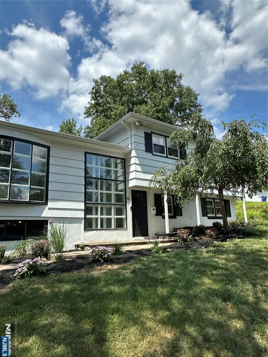 Seller is willing to provide towards closing costs/rate buy down. Nestled on a quiet street just minutes from shopping, business centers, and direct access to NYC, this beautifully renovated home offers the perfect blend of style, space, and convenience. Step inside to discover a bright and airy open floor plan featuring a large living room, formal dining area, and a modern kitchen with a center island, quartz countertops, cabinetry, and stainless-steel appliancesâ€”ideal for entertaining guests or enjoying everyday living. A cozy den with a wood-burning stove provides the perfect retreat for chilly eveningsâ€”especially while cooking wood-fired roasts or homemade pizzas. The enlarged master suite offers a true sanctuary, complete with two walk-in closets, a luxurious private bath with a soaking tub and glass-enclosed shower, plus direct access to a private deckâ€”your own peaceful escape. Downstairs, you'll find an expansive ground-level family room, perfect for gatherings, movie nights, or a play area. Additional highlights include: new flooring, light fixtures, bathroom vanities/fixtures, built-in garage with interior access for added convenience, and multi-zone central air & heating for year-round comfort. Home warranty is included. This move-in ready gem combines thoughtful upgrades with timeless charm. Donâ€™t miss the opportunity to make it yours!