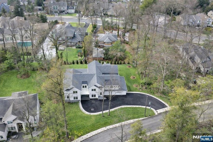 Exceptional new construction mins from NYC, offering approx. 9,600 sq ft of masterfully designed living space across 3 finished levels. Thoughtfully built to balance everyday function w/ luxury living, this home features cathedral ceilings, exposed beams, custom millwork & wide-plank white oak floors throughout. The main level centers around a light-filled open floor plan anchored by a dramatic great room w/ fireplace & 7-ft windows w/ transoms. The dream kosher kitchen stuns w/ dual 12-ft quartz islands, double sinks, double ovens, two integrated refrigerators & a custom walk-in pantry. The adjacent dining area is elevated by a showstopper wet bar. A covered outdoor living room w/ built-in kitchen, fireplace & heaters offers year-round comfort. A private en suite bedroom, formal office & a mudroom complete the main level. The second level features 5 en suite bedrooms, including a palatial primary suite w/ vaulted ceilings, gas fireplace, radiant spa bath, custom walk-in closet w/ center island & private balcony. A large laundry room w/ double washer/dryer units adds convenience. The walk-out lower level offers oversized windows, direct yard access, an en suite bedroom, half bath, multiple recreation spaces & a lounge bar w/ island seating. The 3-car garage features 12-ft ceilings ideal for lifts & two EV charger locations. Finished in Hardie board & stone w/ Pella windows, smart home systems & whole house generator, this property is designed for how you truly live.