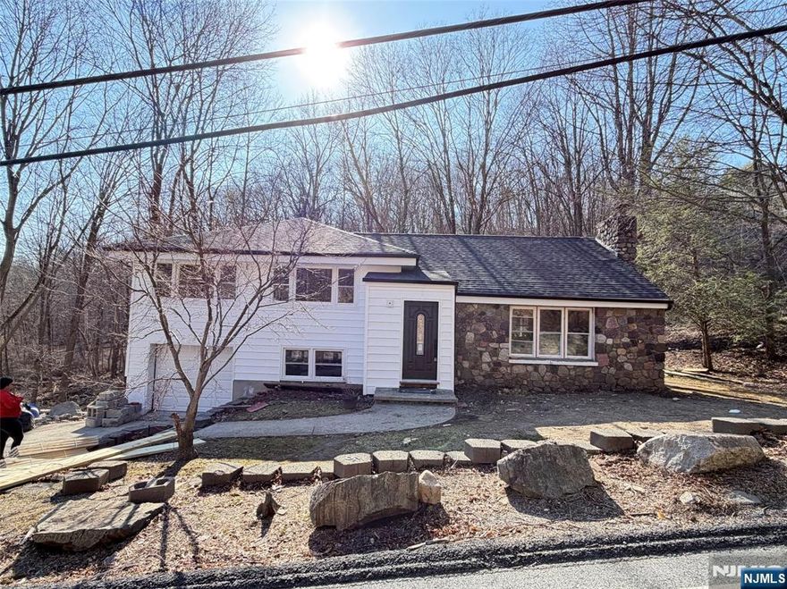 Beautifully renovated and move-in ready, this West Milford home offers bright, open living spaces, waterproof luxury vinyl flooring, and stylish modern finishes throughout. The updated kitchen features white shaker cabinets, quartz countertops with matching quartz backsplash, open shelving, and stainless steel appliances. Spacious living and dining areas flow effortlessly and are anchored by a stunning fireplace. Additional family room and basement spaces offer flexibility for a rec room, home office, gym, or guest area. Updated bathrooms showcase sleek tile work, modern vanities, and contemporary fixtures. Light-filled bedrooms include a lovely primary suite with private bath. Major upgrades include a new roof, new siding, new windows, and a new Roth above-ground oil tank. Complete with a one-car garage and a stream running through the property, this turnkey home blends style, warmth, and functionality.