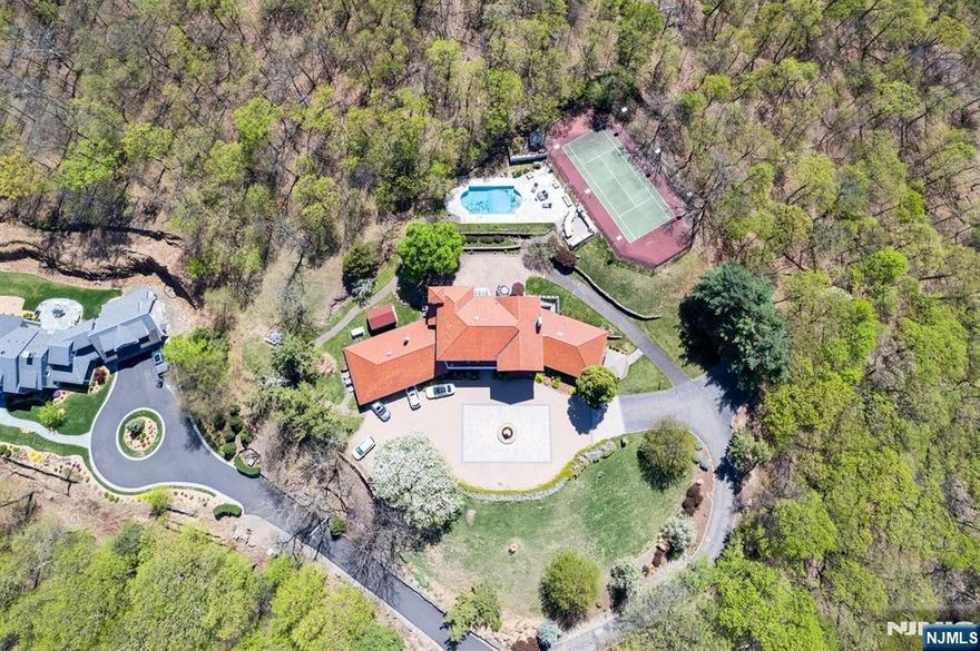 Set high atop 3.2 acres of manicured grounds, this magnificent villa offers resort style living with stunning mountain and lake views. This exceptional property provides unparalleled tranquility and privacy and the feeling of a dream vacation destination, yet is only 30 minutes from NYC. Your private road brings brings you to grounds that are a true private oasis, with a heated pool, tennis court, and a fully outfitted outdoor kitchen. Multiple balconies and terraces create seamless indoor-outdoor living, where the breathtaking views transform with the seasons. The property offers 7,700 square feet of exquisite living space perfect for multigenerational households. With a full interior renovation in 2018, every inch of this extraordinary home reflects master craftsmanship, sophisticated style, and effortless elegance. Designed for grand living and effortless entertaining, the estate features 8 bedrooms and 5.5 baths, a 3-stop elevator, whole-house generator, 5-zone central air, and 7-zone heating. The expansive chefâ€™s kitchen opens into a sun-drenched breakfast room, while the primary suite offers a private balcony with amazing views. Enjoy luxuries such as a cedar closet, sauna, steam bath, wet bar, and changing rooms. In sought-after Franklin Lakes, 912 Cherokee Lane promises an unparalleled lifestyle of distinction, privacy, and beauty. Moments from everything, yet a world away.