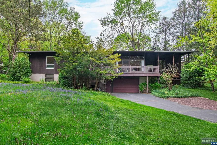 Nestled in the sought-after Montville Township, this rare raised ranch offers a sprawling property w/ exquisite design features throughout. Inside, you'll discover high ceilings & gleaming hardwood FLS that extend across a seamless layout. The living room, a showstopper w/ its floor-to-ceiling stone fireplace & a wall of windows, provides serene views & access to an expansive deck. Kitchen w/ stainless steel appliances has a separate dining area that opens to a charming paver patio perfect for al fresco dining. The family room's French doors reveal a screened-in porch that overlooks a lush backyard, creating a tranquil retreat. Spacious master bedroom suite is a private haven featuring 2 walk-in closets, full bathroom w/ jetted tub, stall shower, dual sink vanity, French doors that lead directly to the paver patio. 3 additional bedrooms & main bath w/ a dual sink vanity complete this home. Lower level includes extra room that's perfect for a home office, gym or guest space.