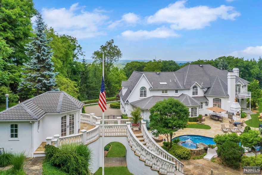 One of the most spectacular properties in Franklin Lakes. This magnificent 4-acre setting is ultra-private, impeccably built & designed for entertaining with a casual style. Outstanding two-story great room has stunning floor-to-ceiling windows, a fabulous classic bar, the gourmet kitchen suite opens to a family room & the striking library has a spiral staircase leading to the wine tasting room. Upstairs houses the luxurious master suite with private balcony, 2 en-suite bedrooms, 2 additional bedrooms and full bath. Fun recreation in the lower level with the awesome indoor basketball court, gym, spa bath, game room & movie night in the 10-seated theater. This special residence offers extraordinary outdoor features including pool with 30 ft. slide, spa, waterfall, outdoor bar, built-in BBQ, pizza oven, heated pool house, lighted tennis court and so much more. Vacation right at your own home!