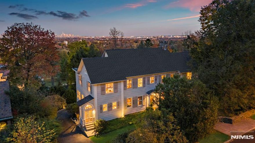Welcome to Altamont, a unique residence atop First Mountain on Montclair's exclusive Lloyd Road. This 1919 Palladian home blends classic craftsmanship with modern updates and offers stunning views of the Manhattan skyline and Eagle Rock Reservation. Antique glass windows bring natural light, highlighting spacious rooms with soaring ceilings, elegant moldings, and three fireplaces. The custom kitchen features hand-cerused white oak cabinets and limestone quartz countertops. The primary suite includes a gas fireplace, dual-facing windows, and a sunroom/office. Five additional bedrooms showcase NYC skyline views. French doors open to a deck overlooking gardens. The walkout garden level offers panoramic skyline views with 10-foot ceilings. Modern amenities include steam heat, zoned central air, and an integrated music system. Altamont is minutes from Montclair's dining, boutiques, and attractions.