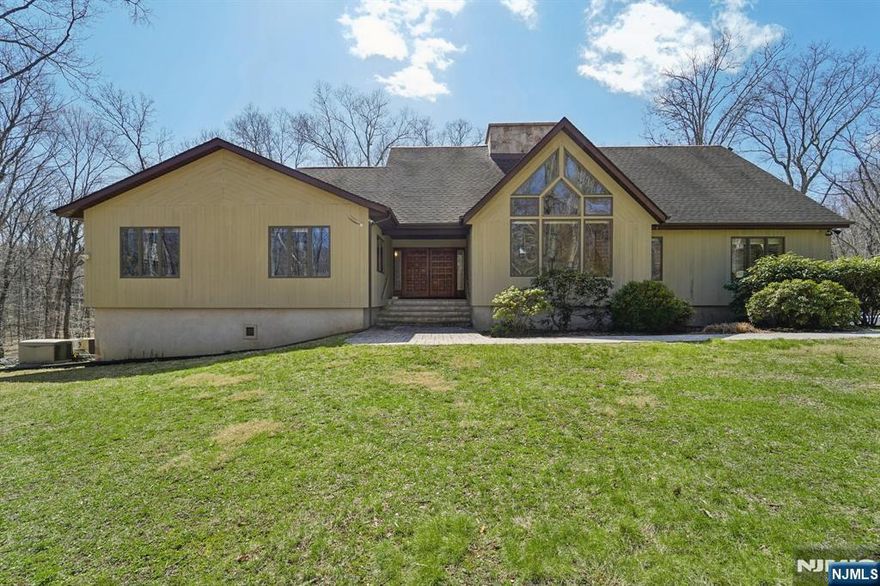 A winding, tree-lined drive sets the tone for this exceptional contemporary retreat set on 5.7 private acres backing to parkland in Chester Township. Thoughtfully maintained and move-in ready, this contemporary expanded ranch delivers single-floor living at its finest four spacious bedrooms, soaring ceilings, and walls of windows flood the open floor plan with natural light. The renovated kitchen features a large center island, country layout and eat-in kitchen perfect for entertaining, while the grand living and family rooms anchor the home's dramatic interior. A loft overlooks the main level and leads to a discreet ladder-access safe room a truly unique feature ideal for secure storage. The luxurious primary suite spans 26x18 with a stunning en-suite bath. Partially finished basement provides room to grow. Outside, enjoy a massive 38x13 deck, hot tub, and beautifully manicured yard. Car enthusiasts and hobbyists will appreciate the rare 5-car garage capacity plus a 12x24 outbuilding ideal for a workshop, collector vehicles, or additional storage. A whole-house natural gas auto-transfer generator adds year-round peace of mind. New gutters throughout. All furnishings available for purchase. Multi-zone heat and cooling, dual-sided wood-burning fireplace in living room and family room, private road setting. Minutes to top-rated W.M. Mendham schools. Extreme privacy, space, and one-of-a-kind features rarely found at this price.