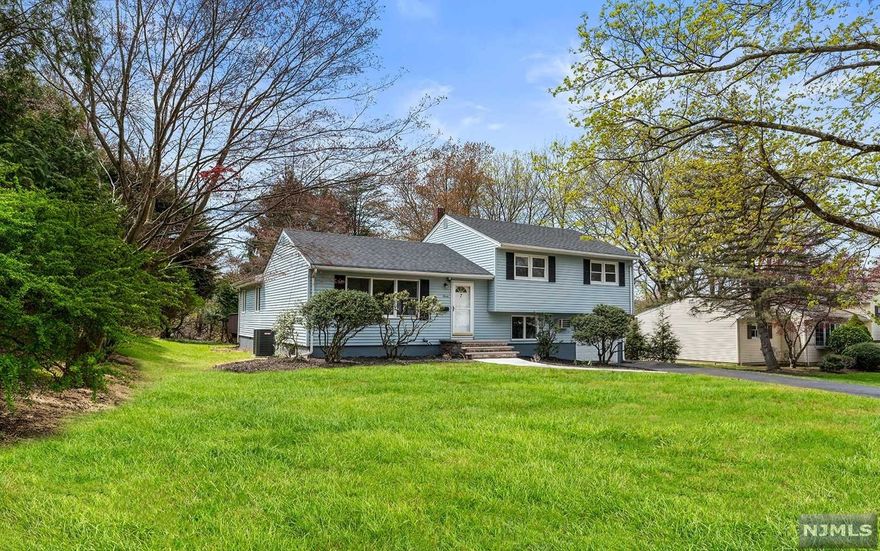 Spaciously expanded split level home on a quiet residential street features 5 bedrooms with 3 full and one half bath. First floor presents an open concept layout with a living room, dining room and kitchen that flows into a huge 20' x 21' great room with cathedral ceiling and skylights. This remarkably large room with walls of windows and access to a large refinished deck is wonderful for entertaining. Second floor offers a primary bedroom with full bath, two bedrooms and a full bath. Lower level is a great option for an extended family with a private entrance to a spacious fourth bedroom with skylight and full bath plus a fifth bedroom/office, a half bath and access to attached garage and semi-finished basement. April 2022 upgrades: New roof, new central air system, refinished deck, new floors on the lower floor and basement, new light fixtures and freshly painted. Approx. 2400 SF of living space, Blue Ribbon schools, minutes to Whole Foods shopping mall, NYC bus and much more!