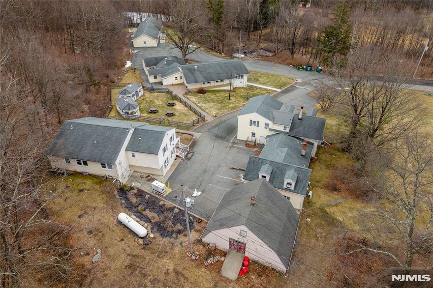 Discover an unparalleled real estate opportunity at 240 Longhouse Dr, West Milford, a sprawling 51.55 acre compound featuring four separate dwellings in a private, wooded setting. This expansive property offers a unique residential layout with established infrastructure, currently serving as a group home. Situated in the R-4 zone, the land provides incredible versatility; however, please note that any transition to a use other than its current designation as a group home requires formal Town Board approval. Potential future uses under R-4 guidelines include community residences, professional offices, and extensive agricultural opportunities. With over 51 acres of pristine Highlands terrain, the property is a candidate for an equestrian center, commercial horse farm, or a boutique agricultural venture such as a winery or craft distillery. Additional possibilities subject to board approval include a bed and breakfast, private campground, or recreational facility. Located minutes from Greenwood Lake and the orchards of Warwick, NY, this property combines significant acreage w/ functional residential units. All information provided is deemed reliable but not guaranteed. The buyer is strictly responsible for performing their own due diligence and verifying all zoning, permitted uses, and property details with the appropriate municipal authorities. Property located in Highlands Act. Tax Exemption in place for current use.