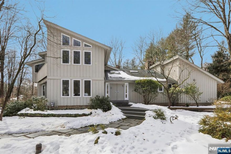 Set in a premier Upper Saddle River location, this custom home offers exceptional craftsmanship, comfort, and timeless appeal. Cathedral ceilings, large sun-filled windows, and elegant custom details create a warm yet sophisticated atmosphere throughout. The custom kitchen features oak cabinetry, an induction cooktop, Sub-Zero refrigerator, KitchenAid microwave/oven, built-in breakfast nook, and adjoining laundry/mudroom. Multiple sliding glass doors lead to an expansive deck and serene koi pond, creating an effortless indoor-outdoor flow for entertaining. The first-floor primary suite includes a beautifully appointed bath with double vanities and an oversized dual-outlet shower. Additional highlights include a three-floor elevator, three fireplaces, custom built-ins, and an integrated entertainment center. Upstairs, a library with built-in bookshelves and a dedicated office with custom workstations add charm and functionality. A full unfinished basement with built-in workbench, second washer/dryer, and a three-car garage complete this distinctive offering. Designed for both elegant entertaining and everyday ease, this is a home that feels as remarkable as it looks; warm, refined, and ready to be experienced in person.