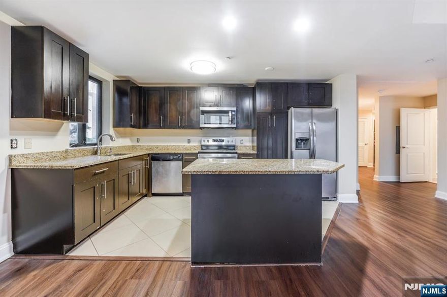 Spacious 2 bedroom, 2 bath residence with a large private balcony, offering approximately 1,300 sq ft of refined living space. This unit features an open concept kitchen with granite countertops, stainless steel appliances, dishwasher, and vinyl flooring throughout. Additional highlights include washer/dryer in unit, walk-in closets, and luxurious marble bathrooms with a Jacuzzi tub and dual vanity sinks. One indoor parking space included, with additional parking available for $150/month. The concrete construction offers enhanced soundproofing and durability. Ideally located with an NYC bus at the corner and NJ Transit train two blocks away, plus close proximity to major highways, shopping, and dining.