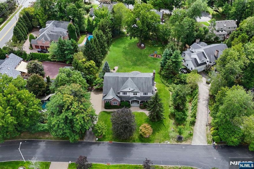 Elegance, privacy & luxury define this expansive Colonial tucked on a serene Demarest cul-de-sac. Nearly .8 acres of lush grounds frame 6 beds, 5.1 baths of refined living space with hardwood floors, soaring ceilings & abundant natural light. The main level features a dramatic 25-ft 2-story foyer, formal living & dining rooms, sun-filled family room & chefs kitchen with French doors to the backyard, plus a 1st-floor en suite. Upstairs, the primary suite dazzles with a sunlit sitting room, 2 WICs & spa bath, joined by another en suite, 2 additional beds with shared bath & a 2nd-floor family room. The finished lower level offers 2 rec areas, bedroom, full bath & storage. 3-car garage, generator, partial wraparound porch & sweeping private yard complete this home, moments from top schools, NYC & houses of worship.