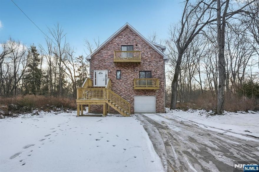 Welcome home to this newly constructed 3-bedroom, 3-bathroom Colonial nestled on a wooded lot in the heart of Wayne, where modern design meets everyday comfort. Step into the inviting entry foyer that opens to a bright, open main living space. The sunlit living and dining room combination features soaring ceilings, skylights, and expansive windows, creating an ideal setting for daily living and entertaining. The dining area flows seamlessly into the beautifully designed kitchen with custom cabinetry, a center island, and brand-new appliances perfect for gathering and making memories. Down the hall, the first floor primary bedroom offers a peaceful retreat complete with walk in closet, full bathroom and access to the private balcony. A second bedroom and full bathroom complete the main level. Retreat upstairs to discover a spacious family room, ideal for relaxing, hosting movie nights or entertaining. Sliding glass doors lead out to the balcony. A generously sized bedroom, full bathroom, and laundry room complete the level. The fully finished walk-out ground level provides exceptional bonus space, perfect for a den, home office, gym, or hobby room. Sliding glass doors from the kitchen lead to a rear deck, ideal for outdoor entertaining, grilling, or al fresco dining surrounded by nature. A 1-car attached garage completes this thoughtfully designed new construction home, offering space, style, and comfort indoors and out.