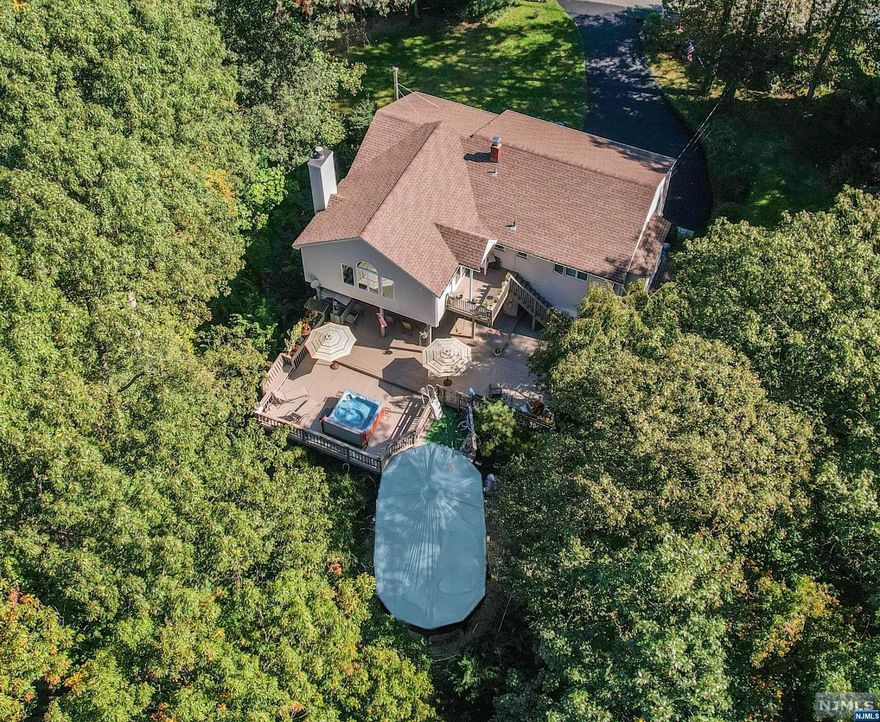 Over 2,400 sq. ft of living space, privately set on 1.3 acres, on dead end street.Top rated school system. Move-in ready.Pool. Newer 3Br septic & roof. Updated boiler & windows.Wood floors.Stunning great rm addition w/palladium window & tons of natural sun light overlooking beautiful rear wooded yard w/expansive entertaining area. Walk-out lower level to large covered deck, hot tub, pool & tranquil water feature. Master bedrm suite w/full bath & walk-in closet & add'l full wall closet. Upper level of home is complete w/formal living & formal dining rm, eat-in kitchen w/breakfast bar, separate dining area & pantry. Great rm w/high ceilings & wood-burning fireplace. Sliders to deck & outside entertaining area. Lower level, original build had 4th bedrm & is currently open to family rm w/wd burning stove, powder rm, laundry rm & utility rm. Perfect for multi-generational living.Minutes to schools, town center, restaurants, shopping, NJ transit, & major highways. Easy NYC commute.