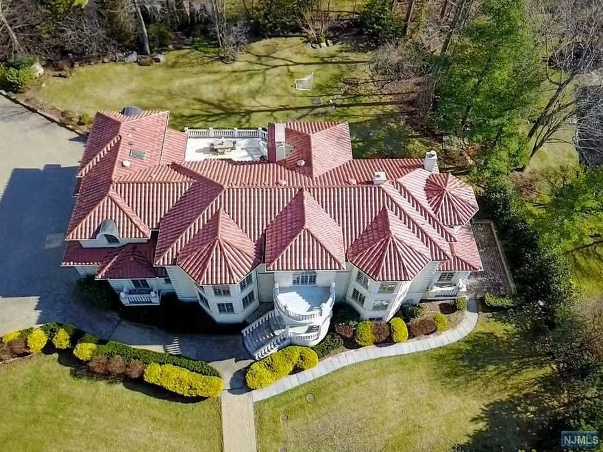 GORGEOUS MEDITERRANEAN COLONIAL SITTING HIGH ON A LUSHLY-LANDSCAPED CORNER PROPERTY IN PRESTIGIOUS ALPINE. BRIGHT, OPEN FLOOR PLAN WITH A GRAND MARBLE FOYER, LIBRARY/GUEST ROOM W/FIREPLACE, BANQUET-SIZED DINING ROOM AND A GOURMET CHEF'S KITCHEN FOR ALL YOUR ENTERTAINING NEEDS. IMPRESSIVE GREAT ROOM W/ VAULTED CEILINGS, ARCHED WINDOWS & FRENCH DOORS THAT OPEN TO A LARGE STONE TERRACE OVERLOOKING NEARLY 1 ACRE OF FLAT YARD. A BUTLER'S PANTRY/MUDROOM & ORNATE FULL BATH COMPLETE THE FIRST LEVEL. UPSTAIRS AMENITIES INCLUDE A LUXURIOUS PRIMARY RETREAT W/SITTING AREA, FIREPLACE, WALK-IN CLOSETS, MARBLE BATH W/STEAM SHOWER, JACUZZI & RADIANT HEATED FLOORS, 3 MORE PRIVATE EN-SUITES. THE WALK-OUT LOWER LEVEL HAS RECREATION W/MEDIA RM, BAR, FITNESS AREA. ALSO 4-CAR GARAGE W/ WIDE PAVERS DRIVEWAY, PROFESSIONALLY-LANDSCAPED PRIVATE GROUNDS. WITH LOW TAXES, PROXIMITY TO MANHATTAN & GREAT SCHOOLS, ALPINE IS TOP-RANKED BY FORBES. NOTHING TO DO BUT MOVE IN AND ENJOY THE BEST OF BERGEN COUNTY!