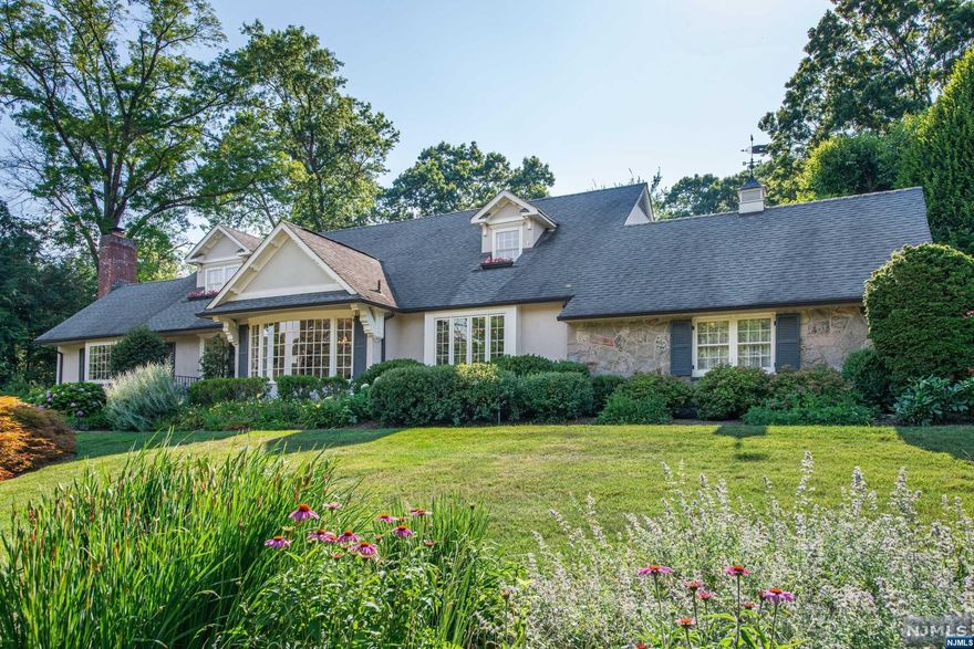 This elegant expanded ranch in Ridgewood's prestigious Old Country Club neighborhood offer offers a grand entrance with a formal living and dining room streaming with natural light. The large living room showcases a wood-burning fireplace with built-ins, perfect for formal or informal living. A cherry-paneled library with coffered ceiling, and exit to the award-winning gardens and pool area offers a handsome space to unwind. The home features a unique 1st-floor primary suite with gas fireplace, providing convenience and luxury. The eat-in kitchen is a chef's delight with high-end appliances. With 3 bedrooms and 3.5 baths, there is ample space for comfortable living. Step outside to your private oasis with a resort-style salt-water pool surrounded by blue-stone, a stunning waterfall, and spa set on a beautifully landscaped .46-acre lot. The full finished basement offers additional living space and versatility. An attached 2-car garage completes this exceptional property.