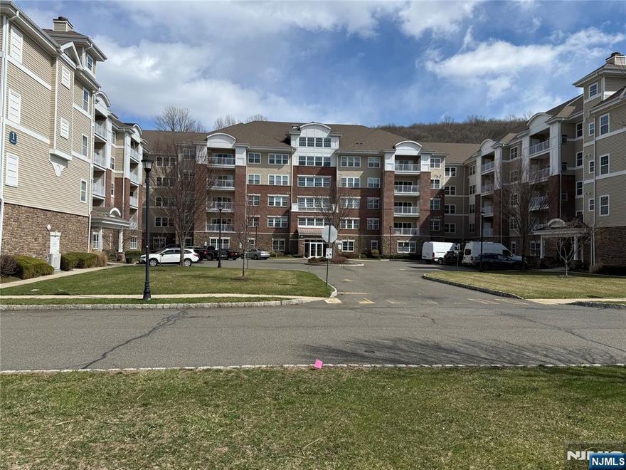 Largest 2 bedroom 2 bathroom model, 2119 SF Westbrook end-unit in Wanaque Reserve, a Del Webb 55+ active adult community, is in the newest building. This move-in ready home boasts hardwood flooring, a spacious 20x20 primary bedroom ensuite featuring a full bath, tray ceiling and two walk-in-closets. There' a a second bedroom, full bath, eat-in-kitchen with stainless steel appliances, granite countertops, and a tiled backsplash. The living room, dining room and den are highlighted by French doors for added elegance, and the living room's sliding doors lead to a private balcony with seasonal views. Additional features include a larger den, laundry room & 2nd bedroom, upgrades such as three pot drawers, extra upper cabinets, a laundry area with countertop and cabinetry, wine refrigerator, new hot water heater, and new refrigerator. The home comes with two deeded parking spaces, a 6x10 deeded storage unit on the same floor, and 24-hour security. Residents enjoy access to a 20,000 SF clubhouse offering a cafe, ballroom, gym, theater, sauna, indoor and outdoor pools, plus more than 45 clubs & activities, including travel club (cruises, trips, casino outings), tennis, pickleball, canasta, poker, golf, and more. Wanaque Reserve provides residents with a luxurious lifestyle focused on modern comforts, security, and community spirit. Recent renovations have created a fresh, updated living environment.