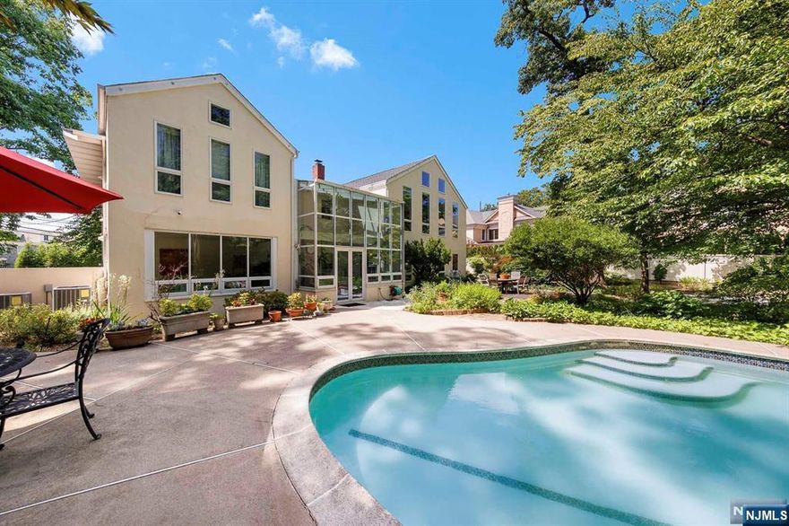 Welcome to the East Hill of Englewood, a stunning neighborhood just ten minutes from Manhattan. This spacious home features a two-story solarium, flooding the interior with natural light. Set on a .7-acre lot, the flat, fenced-in yard is beautifully landscaped and includes a heated in-ground gunite pool, perfect for relaxation and gatherings. Prestigious corner lot location where the front door faces N Woodland and the 2 car garage faces a quiet cul-de-sac. The home offers privacy and a peaceful living environment. Recent updates include new dishwasher, new range, new hood, new laundry machines, new circular driveway, new roof & insulation. Enjoy the best of suburban tranquility and urban convenience in this luxurious East Hill property. See virtual tour link for a comprehensive video tour, floor plans, and additional photos.