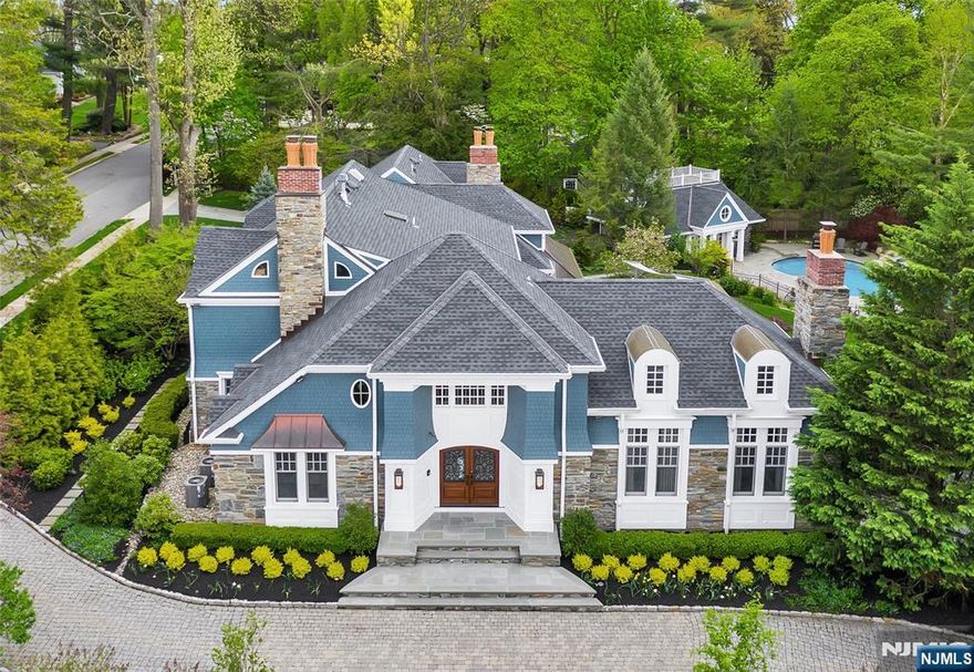 Poised in the prestigious Heights section of Ridgewood, this masterfully designed estate offers over 10,000 SF of sophisticated living space on nearly an acre of resort-like grounds. A true architectural sanctuary, the smart-integrated residence opens with a gorgeous 2-story foyer that leads to a great room at the home's focal point, with soaring ceilings and one of the property's 5 fireplaces. The heart of the home is a culinary dream - a gourmet kitchen anchored by dual 5'x9' Calcutta Gold marble islands and professional-grade Wolf/Sub-Zero appliances, including a built-in Earthstone pizza oven that opens to a family room with a fireplace, both lined with floor-to-ceiling windows and French doors overlooking the private backyard. The versatile floor plan also includes a banquet-sized dining room, stately den, ensuite bedroom/office, mudroom, and access to the 3-car garage. Luxuriate in the primary suite featuring a private balcony, and dual full bathrooms, both with radiant heat and a massive California closet. Entertainment reaches new heights in the expansive basement, boasting a wine room and a state-of-the-art movie theater. Transitioning outdoors, the fenced yard hosts a freeform gunite pool, a massive bluestone patio, and a designer kitchen outfitted with a full suite of Lynx appliances. Completing the home is a fully equipped pool house with a living room, kitchen, laundry, and bedroom/loft - all just a short stroll from downtown, schools, and the train to NYC.
