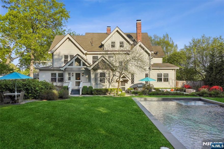 A one-of-a-kind Queen Anne estate blending old-world charm with quiet luxury, just one block from Upper Montclair's train, restaurants, shops, and parks. From the enchanting front porch to the diamond-paned and leaded glass windows, this home is rich with architectural detail. Inside, elegant moldings and gorgeous wood floors frame gracious living spaces, including a sunken living room with gas fireplace, a library with private porch access, and a formal dining room with fireplace. The chef's kitchen is a dream - custom cabinetry, professional appliances, and a large island flows into a playroom and then sun-filled family room. The serene primary suite features a spa-inspired bath, dressing room, and dual walk-in closets. Two additional bedrooms on the second floor, one is ensuite; the third floor offers two more bedrooms and a full bath. The finished lower level includes a screening room, wine cellar, rec room, and full bath. Something for everyone all weekend! Outside, enjoy a private resort-style retreat: Waterworks-tiled pool and spa, lily pond, waterfall patio, and lush perennial gardens. With radiant heat, 5-zone HVAC, generator, and whole-home audio this is luxury living at its most livable.