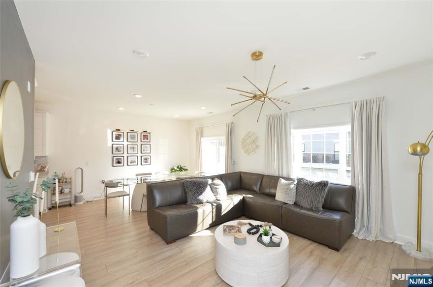 Welcome to this ultra-modern townhome located in the sought-after The Parke at Little Falls, freshly built just two years ago and offering a seamless blend of style, comfort, and convenience. This sun-drenched residence instantly welcomes you on the ground level with a stunning designer eat-in kitchen featuring pristine white cabinetry, sleek stainless steel appliances, and elegant finishes. The kitchen flows effortlessly into the open-concept dining and living areas, where expansive windows flood the space with natural light and provide direct access to a private patio, the perfect setting to relax or entertain. The first floor also offers a modern full bathroom, a dedicated laundry room, and convenient access to the private garage. Upstairs, the home continues to impress with a generous primary bedroom adorned with modern wallpaper, a tasteful chandelier, and a beautifully appointed en-suite bathroom. An additional spacious bedroom, equally stylish with modern finishes and chandelier lighting, is complemented by a full hallway bathroom. Ideally located just minutes from Willowbrook Mall, this home offers easy access to premier shopping, dining, Costco, coffee shops, bakeries, and effortless transportation options with a direct route into NYC. This move-in-ready townhome delivers modern luxury and everyday ease, one you wonâ€™t want to hesitate to call home.