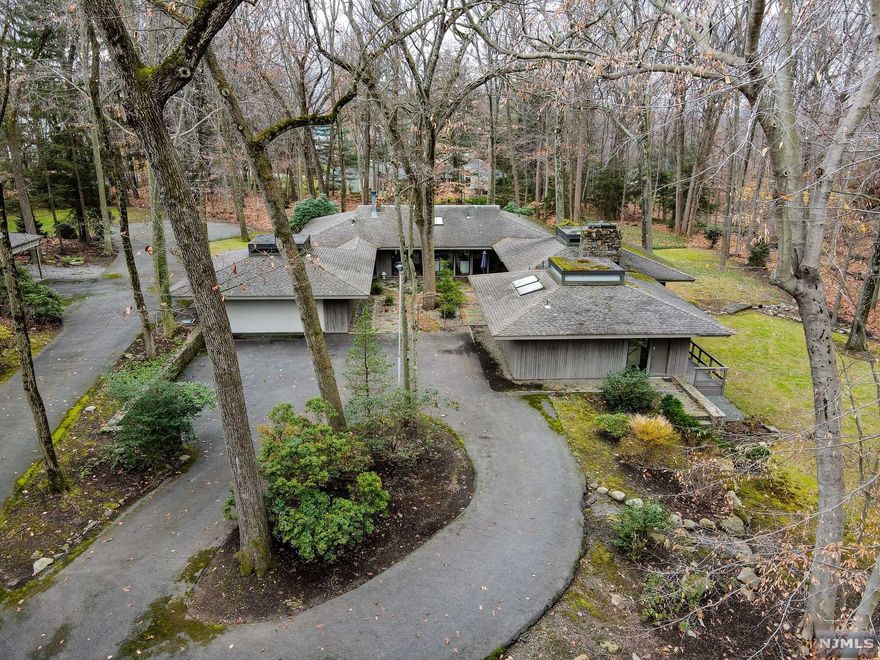 Welcome to "One Duck Pond Road"! Custom built Frank Lloyd Wright-inspired home, sitting on a highly desirable tree covered 3.579 acre lot in the old Beechwood Farms area of Alpine. Main living spaces feature original redwood ceilings and floor to ceiling windows throughout. The home includes a recently updated kitchen with fireplace and skylight, large dining room and living room with beautiful wooded views, doors to a wrap around deck, and a running stream nearby. Master suite has its own sitting area with an ample master bath in addition to 4 other bedrooms. Lower level living area has 2 large family/game rooms, a home office, wet bar, laundry, storage and a sauna with shower. 3 zone heat and forced hot air, 2.5 septic fields, 2 sump pumps, 3 hot water heaters, 2 car garage and 2 car carport. Update the existing home or build new on this spectacular property!