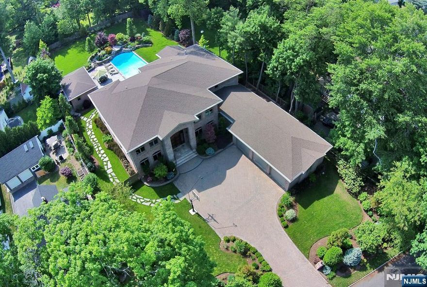 Located in one of Cresskillâ€™s most sought-after neighborhoods, this exceptional estate offers 5 bedrooms, 6 full bathrooms, and 1 half bath across multiple levels designed for comfortable living and entertaining. A dramatic two-story foyer leads to a custom kitchen with stainless steel appliances, dual islands, eat-in dining area, and walk-in pantry, opening to a spacious family room. A formal dining room with bar, private office, sitting room with soaring ceilings connected to a custom theater, bedroom with full bath, laundry room, and powder room complete the main level. The second level features a private primary suite with sitting area, fireplace, balcony, and spa-like bath, along with three additional en suite bedrooms. An unfinished lower level offers future potential. Outside, enjoy a private backyard oasis with custom pool, waterfall, and finished pool house with wet bar and full bath. A three-car garage completes the home.