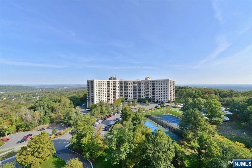 Experience refined living in this exquisite open-concept end-unit condo, filled with natural light and designed for effortless entertaining. The spacious living and dining areas feature expansive Thermopane windows and sliding doors that showcase sweeping panoramic sunset views over rolling hills and a serene, wooded landscape. Step outside to your private balcony - perfect for unwinding at dayâ€™s end. The adjoining eat-in kitchen offers sleek white cabinetry, granite countertops, appliances, and the convenience of an in-unit washer and dryer. The primary suite includes two walk-in closets, a dedicated dressing area, and a private en-suite bath. A second bedroom easily adapts as a guest room, home office, or den. Recent upgrades include neutral carpeting and fresh paint throughout. A floor-level storage unit provides additional storage. Monthly maintenance covers all utilities. Residents enjoy an exceptional suite of amenities, including 24/7 concierge and valet service, party and card rooms, a library, a full-building backup generator, a fitness center with saunas and showers, a heated Olympic-size pool, a BBQ area, a 7-cup putting green, a tennis court, and a basketball/pickleball court. Ideally located near major highways, NYC bus routes, and the Montclair train station, with shopping, dining, and parks just minutes away. A timeless yet contemporary home - make it yours today!