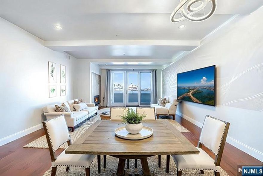 Beautifully updated 1-Bedroom + Den, 2-Bathroom Condo with walk-in closet offers breathtaking views of the Manhattan skyline and Hudson River. The kitchen is fitted with granite countertops, a built-in cooktop, and rich espresso cabinetry. The Living room centerpiece features a custom museum-quality architectural art wall installation with programmable LED backlighting. A wood-burning fireplace creates the perfect cozy retreat, while the oversized balcony invites you to unwind and take in the stunning scenery. Enjoy the convenience of in-unit washer/dryer, garage parking, and building amenities including; a gym, indoor heated pool, and 24-hour concierge. With Whole Foods, the Ferry, Light Rail, and bus service just steps away, truly one of the best locations on the waterfront.